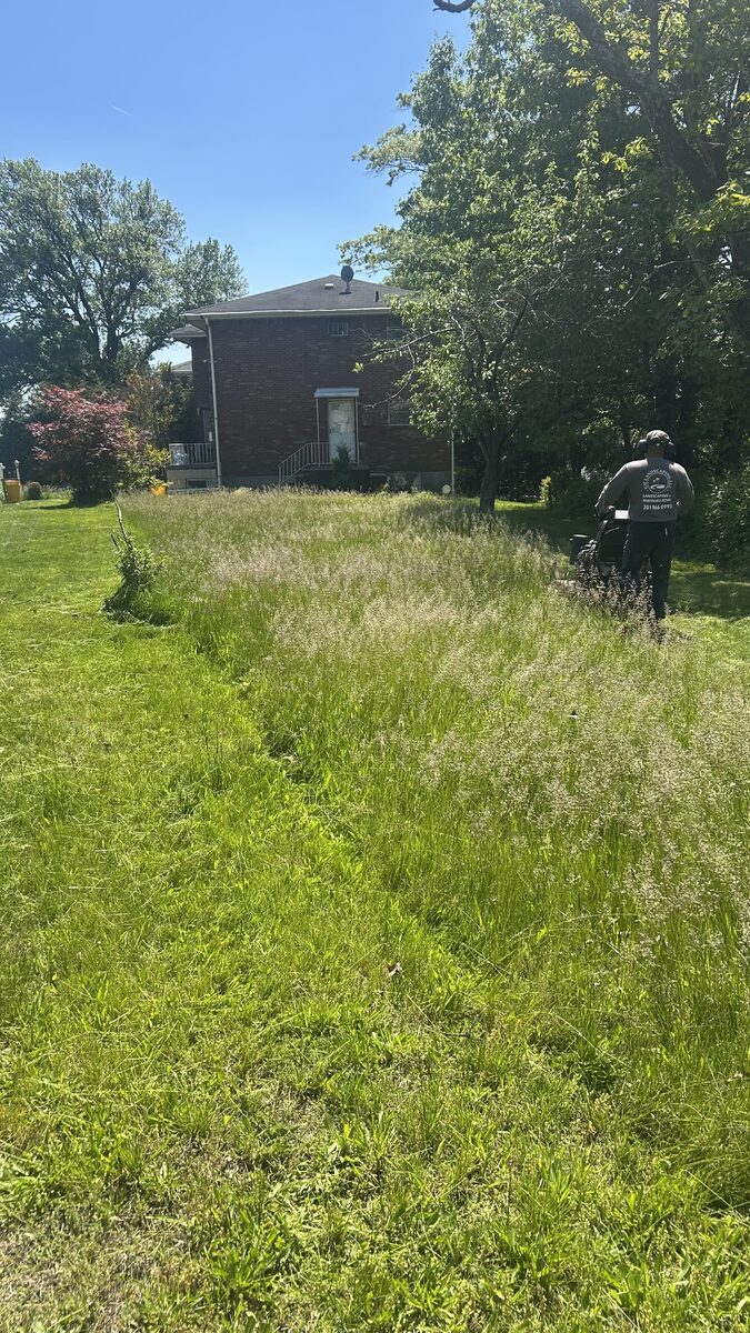 GH Landscaping LLC crew member mowing a property